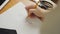 Close-up of a woman`s hand, a fashion designer drawing sketches of clothes in the atelier