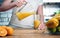 Close up of woman`s hand holding glass carafe or jug. Drinking orange juice at home in the kitchen. Healthy eating, morning