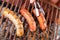 Close up of woman s hand holding a tongs turning the grilling sausages on barbecue grill. BBQ. Bavarian sausages