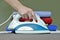 Close-up of woman\'s hand ironing clothes on the table against th