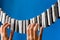 Close-up of a woman`s hand playing the imaginary piano made from clothes pins on blue paper background