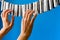 Close-up of a woman`s hand playing the imaginary piano made from clothes pins on blue paper background