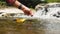 Close up of Woman`s hand putting paper boat on the water and pushing it away with reflection sunshine in the water background, as