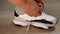Close-up of a woman's hand tying the laces on a white sneaker. Side view. Light wooden floor. Active lifestyle.