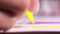 Close-up of woman`s hand with yellow felt pen drawing some figure on the paper sheet at the table. Action. Creativity