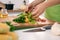 Close up of woman`s hands cooking in the kitchen. Housewife slicing fresh salad. Vegetarian and healthily cooking