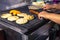 Close-up of woman\'s hands cutting a chorizo and preparing Colombian arepas and empanadas on a grill