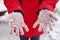 Close up of woman's hands in gloves with snow. Unrecognizable woman playing with snow on walk in wintertime.