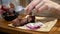 Close up woman`s hands with knife and fork cutting meat in dish on table in a restaurant