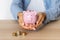 Close-up of a woman\'s hands with a piggy bank on the office table. crisis and inflation. Cost Management