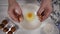 Close-up, woman`s hands poured egg yolk from white shell into a white plate