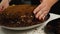 Close-up of a woman's hands sprinkling a cream-dipped cake with dark biscuit crumbs. Making a cake. Home bakery