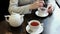 Close-up woman`s hands stirred with a spoon sugar in tea. Teapot and cups on table.