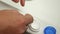 Close-up of a woman's hands taking a contact lens out of a container. The lens is placed on her finger to put on her