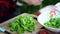 Close up of woman\'s hands tearing lettuce and putting in plate.