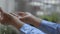 Close up woman\'s hands wearing blue raincoat playing with the rain in front of the house.