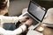 Close-up of woman`s hands working on laptop, screen space for design layout. Woman having coffee at modern cafe, wooden slab table