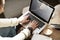 Close-up of woman`s hands working on laptop, screen space for design layout. Woman having coffee at modern cafe, wooden slab table