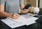 Close up of woman`s hands writing on a paper with hold smartphone on the table and working calculating monthly home expenses, tax.