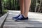 Close-up of a woman\'s legs in blue sneakers on a boardwalk footpath. Forest in the background. Brokenhead Wetland Trail.