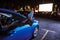 Close up of woman s legs dangling out a car window parked in front of a big white screen at drive in cinema