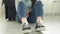 Close-up of a woman's legs in sneakers, a woman sits on the floor and moves her legs