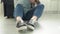 Close-up of a woman's legs in sneakers, a woman sits on the floor and moves her legs