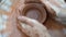 Close-up of a woman's potter's hands creating a bowl on a footed old circle. Form the shape of a pottery out of