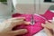 close up, woman sews clothes or accessories from pink fabric in workshop
