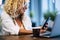 Close up of woman smiling and looking at her phone with her laptop and coffee - beautiful and worker adult lady using and working