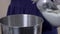 Close-up of a woman with a spatula pours flour into a bowl.