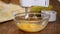 Close up of woman standing at kitchen table pouring sugar into deep plate with eggs then whisks eggs with a mixer.