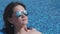 Close-up of woman sunbathing near pool, blue water background