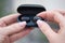 close-up of a woman taking out a black wireless earbud from his charging box. Female hands touching