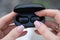 close-up of a woman taking out a black wireless earbud from his charging box. Female hands touching