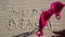 Close up of woman throwing bra at nude beach sign written on sand. Concept of sunbathing naked on the sandy ocean beach.