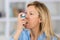 Close-up woman using asthma inhaler in living-room