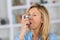 Close-up woman using asthma inhaler in living-room