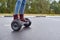 Close up of woman using hoverboard on asphalt road. Feet on electrical scooter outdoor