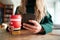 Close Up Of Woman Using Mobile Phone With Reusable Takeaway Drink Cup Sitting At Table  In Cafe