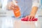 Close Up Of Woman Using Spray Polish To Clean Kitchen Surface