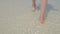 Close up of a woman walking on exotic white sandy beach.