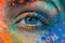 Close-up of a womans beautiful blue eye adorned with vibrant, multicolored makeup, creating a mesmerizing and artistic