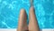 Close up of womans legs playing with water in swimming pool, pure blue water