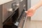 Close up of women hand opening the oven door to control the roast.