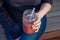 A close up of a women holding a smoothie in a glass jar with a clear, food-grade silicone straw