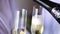 Close up. Women holds two glasses in which champagne is poured. A man pours champagne into glasses. Champagne spill