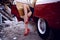 Close up of a women legs in red shoes heels sitting inside on vintage red car on iron dump background. Horizontal view.