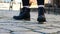 Close up women`s feet in black boots on cobblestone pavement