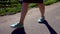 Close-up of women`s feet in sneakers. The girl is on the asphalt path along the waterfront.